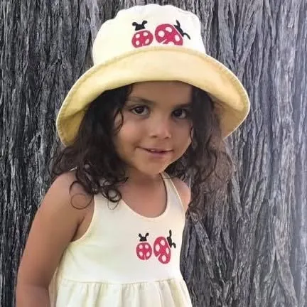 Smiling girl in a cream bucket hat stamped with ladybugs